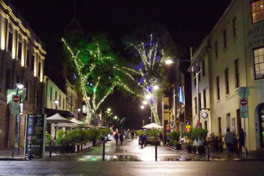 image of a night time tree lined street with outdoor cafes